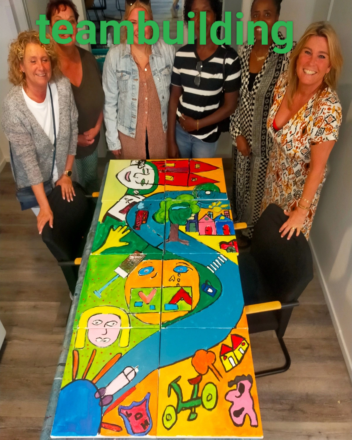 Een groep deelnemers staat trots achter een gezamenlijk kleurrijk schilderij in het atelier.